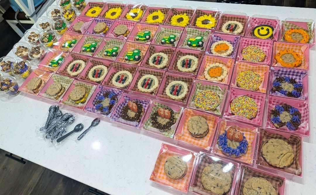 Trays of decorated cookies and cookie cups with sunflowers, tractors and party themes